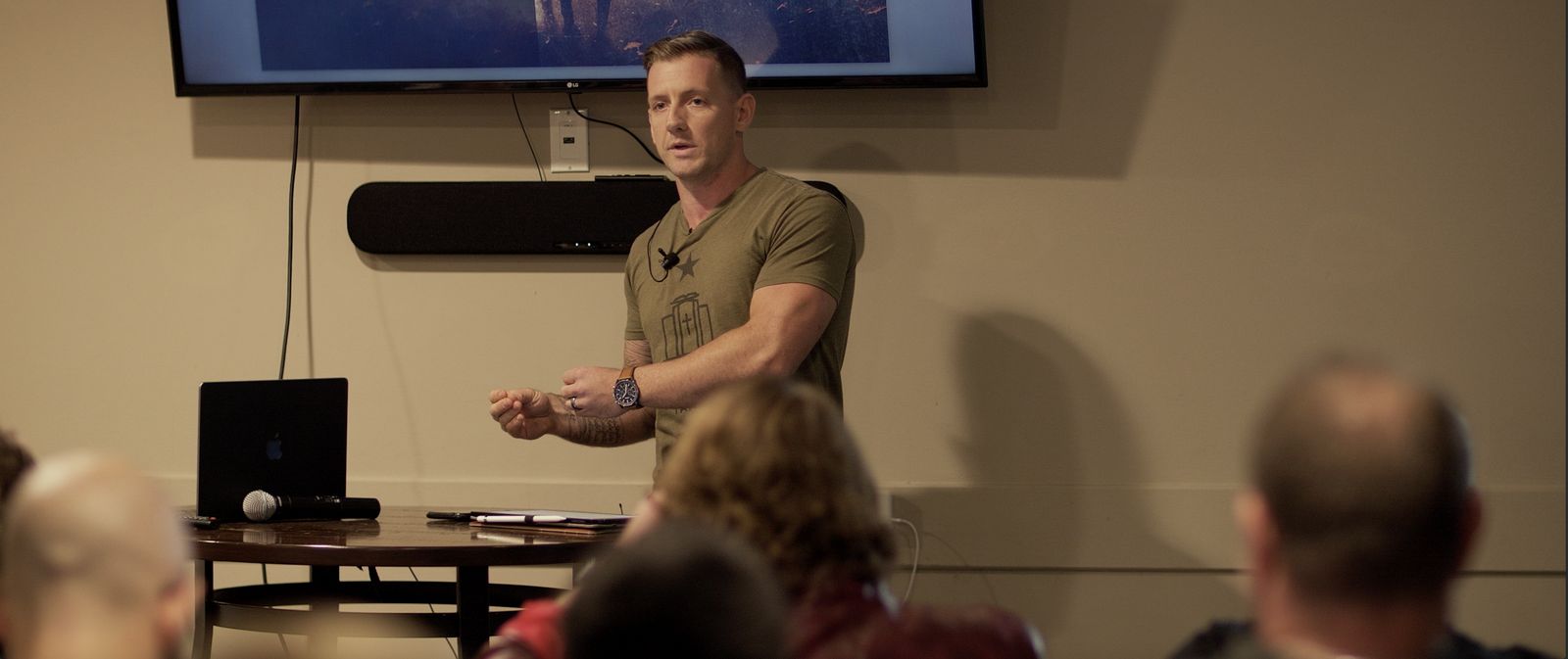 Jeremy Bundy speaking to a seated audience in front of a presentation screen